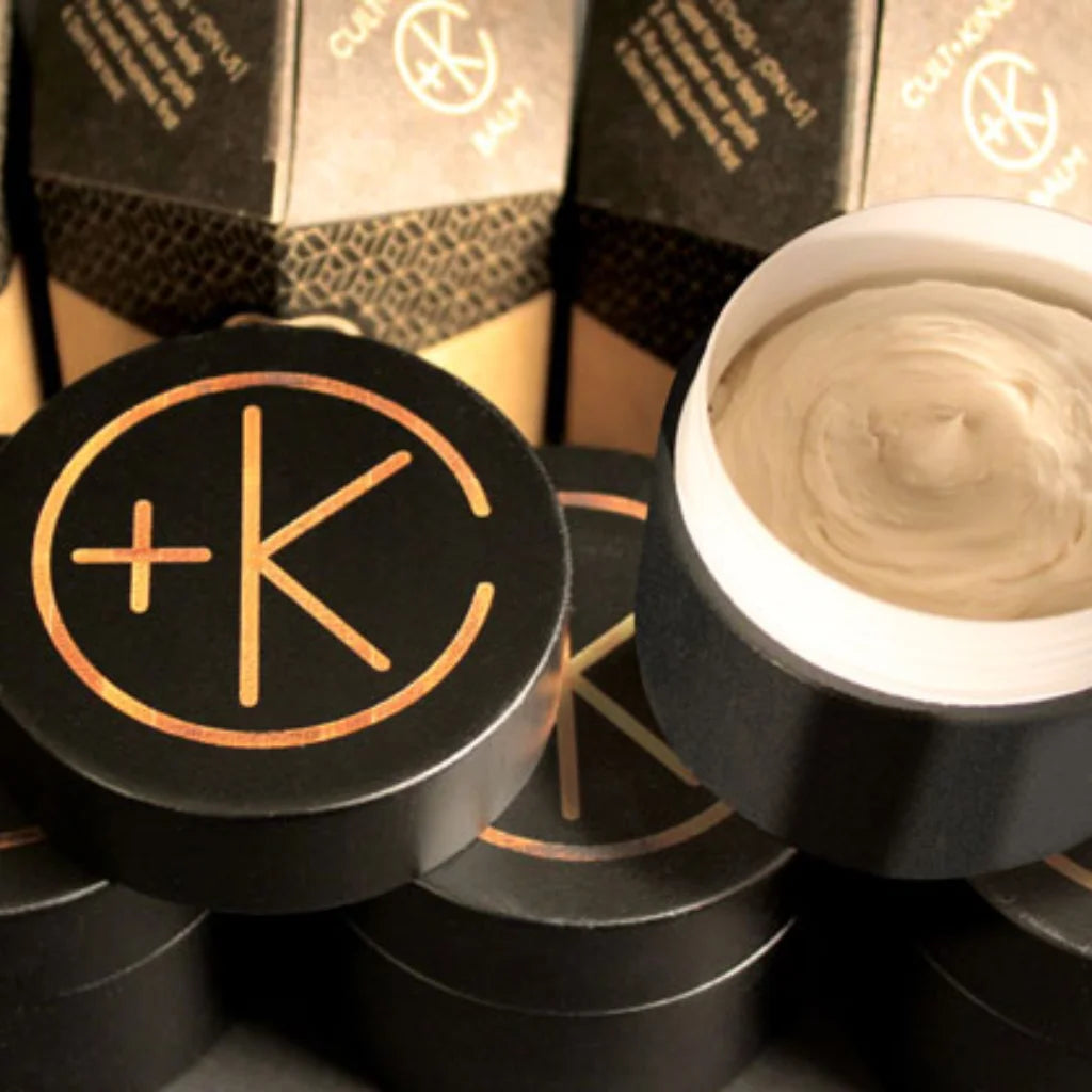 Cosmetic product with a logo on a black container, surrounded by branded boxes.
