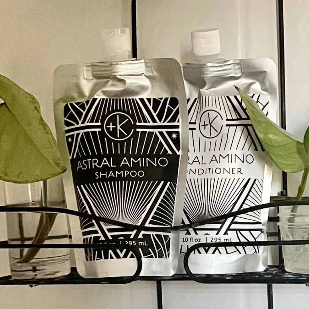 Cult & King Astral Amino shampoo and conditioner bottles on a shelf with plants in the background
