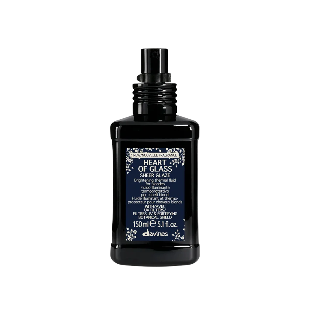 A bottle of Davines Heart of Glass Sheer Glaze hand cream, featuring a black rectangular bottle with a dark blue label and a black spray nozzle, set against a plain white background.
