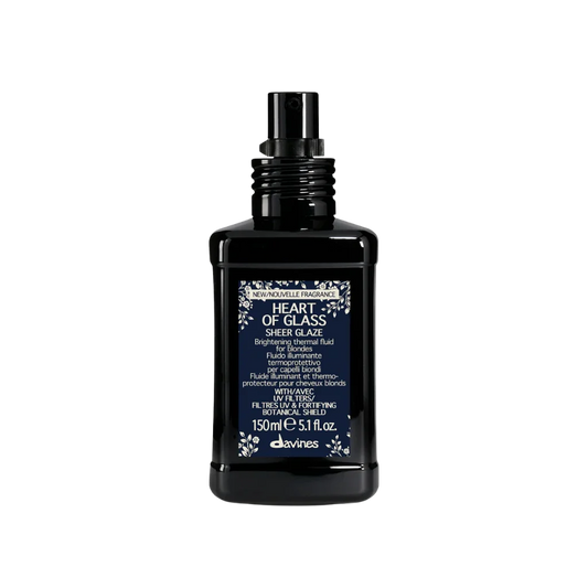 A bottle of Davines Heart of Glass Sheer Glaze hand cream, featuring a black rectangular bottle with a dark blue label and a black spray nozzle, set against a plain white background.