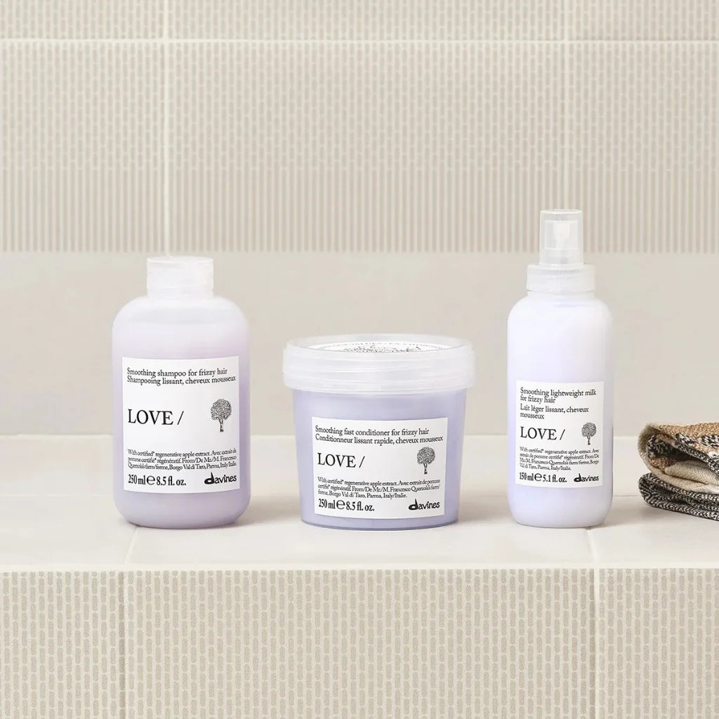 Three Davines hair care products on a bathroom shelf with a tiled wall background.