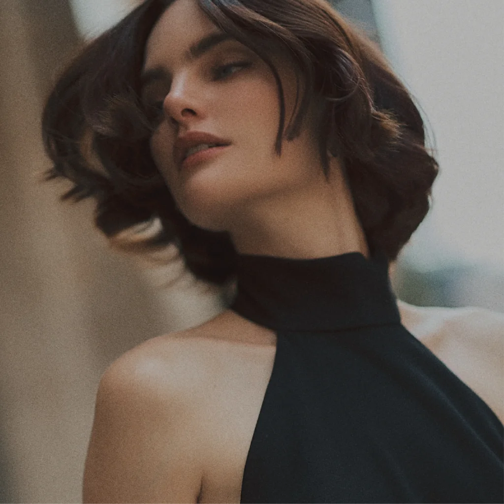 Woman with short brown hair wearing a black high-neck top against a neutral background
