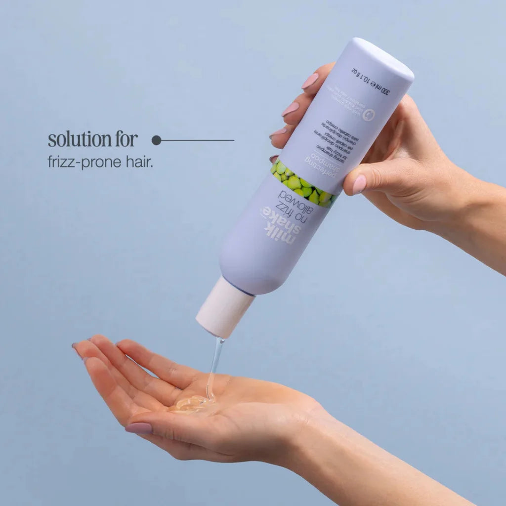 Hand holding a bottle of hair care product with a blue background